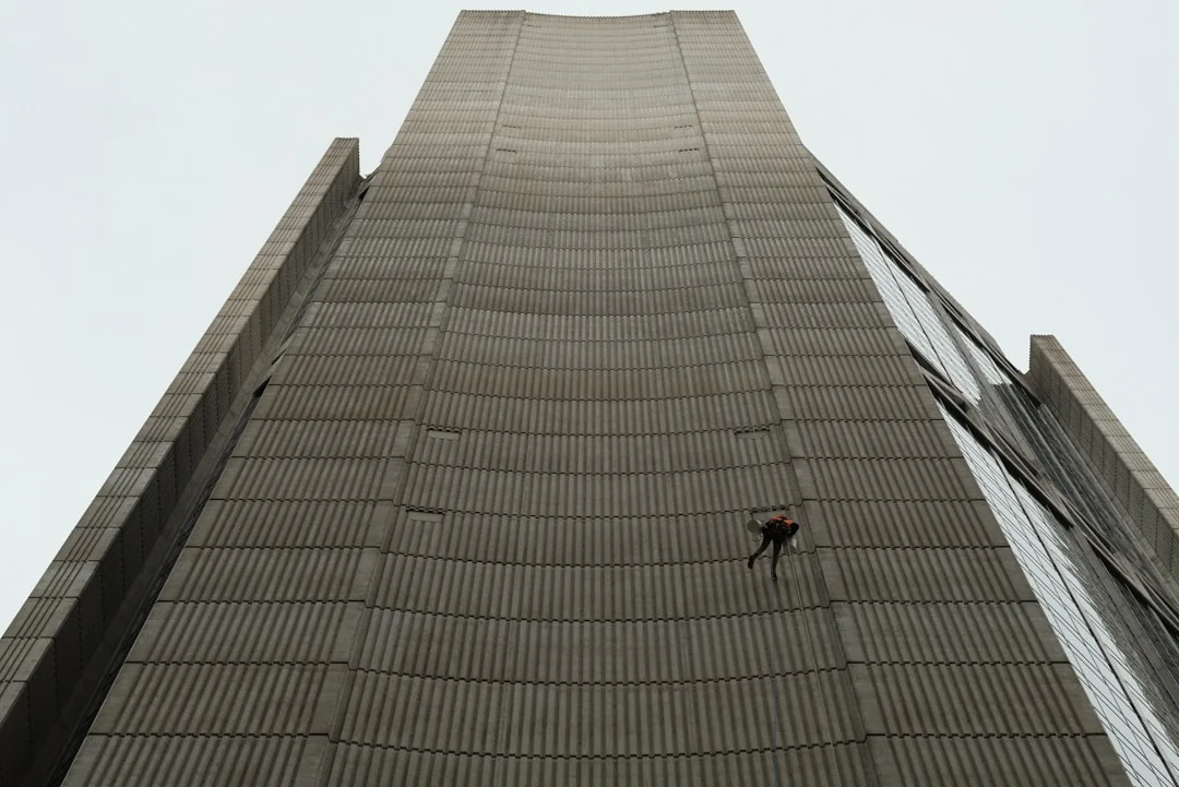 A man cleaning skyscraper windows with a harness, showcasing urban high-rise work.